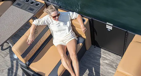 Aerial view of a woman sitting on a stern seat of a Godfrey Monaco pontoon boat.