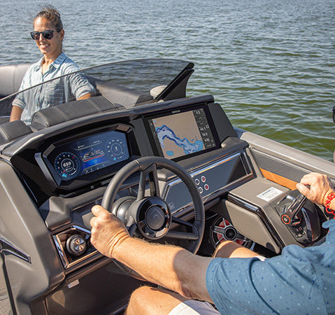 A man sitting at the all-new helm on a Godfrey Sanpan pontoon boat.