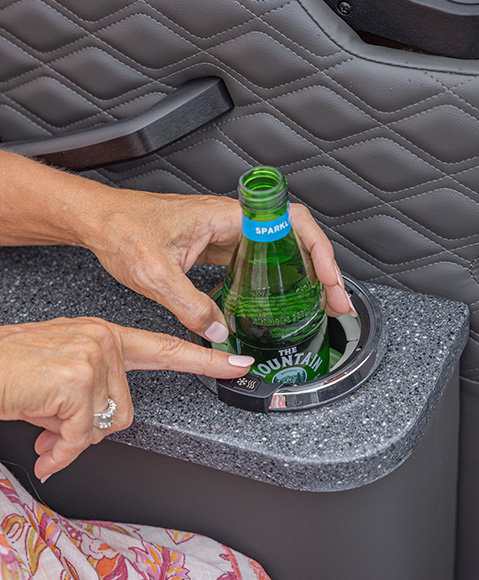 A close-up of a person pressing a heating/cooling button on a cupholder with a beverage in it on a Godfrey Sanpan pontoon boat