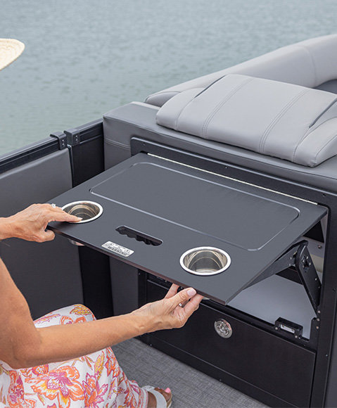 A person pulling open a fold-out table on a Godfrey Sanpan pontoon boat