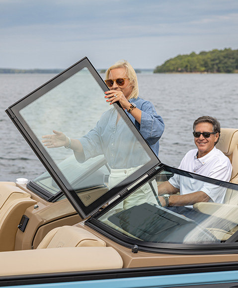A woman folding open a glass windshield on a Godfrey Sanpan pontoon boat