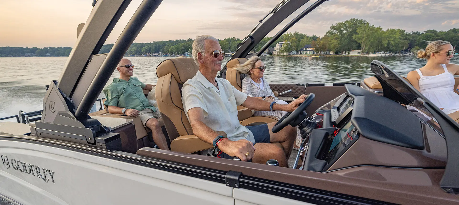 A man smiling while sitting at the helm and cruising the lake on his Godfrey Sanpan pontoon boat.