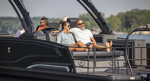 A couple smiling while relaxing on the flip lounge seat on the stern of a Godfrey Sanpan pontoon boat.
