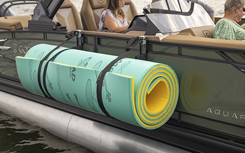 Close-up of a rolled-up water mat attached to the side of a Godfrey pontoon boat by a toolless boat accessory attachment system