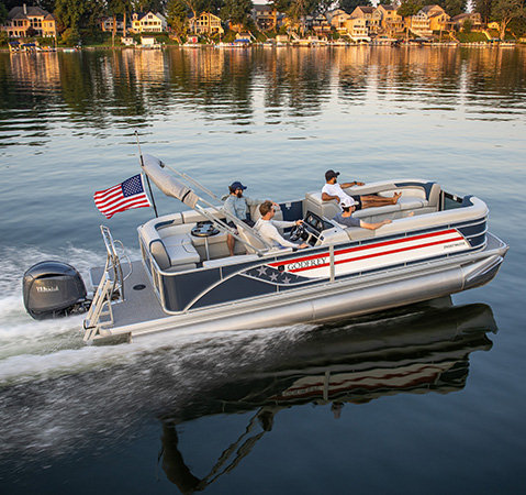 Godfrey Sweetwater pontoon boat with patriotic graphics and an American flag carrying passengers across calm water.