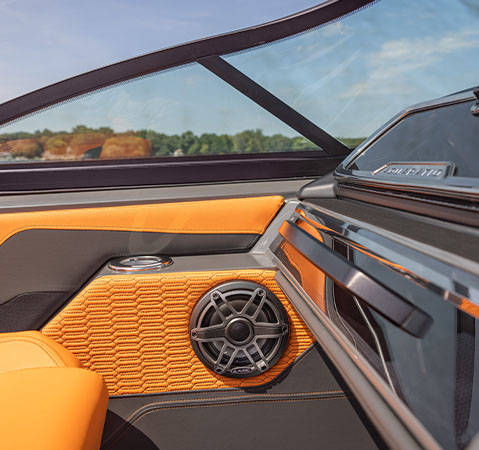Godfrey AquaPatio pontoon boat interior featuring orange quilted upholstery, a cup holder and JL Audio marine speaker.