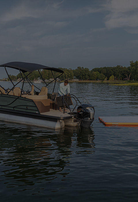 Family smiles on the back of a Godfrey Pontoon boat, wearing Godfrey Pontoon accessories and apparel.