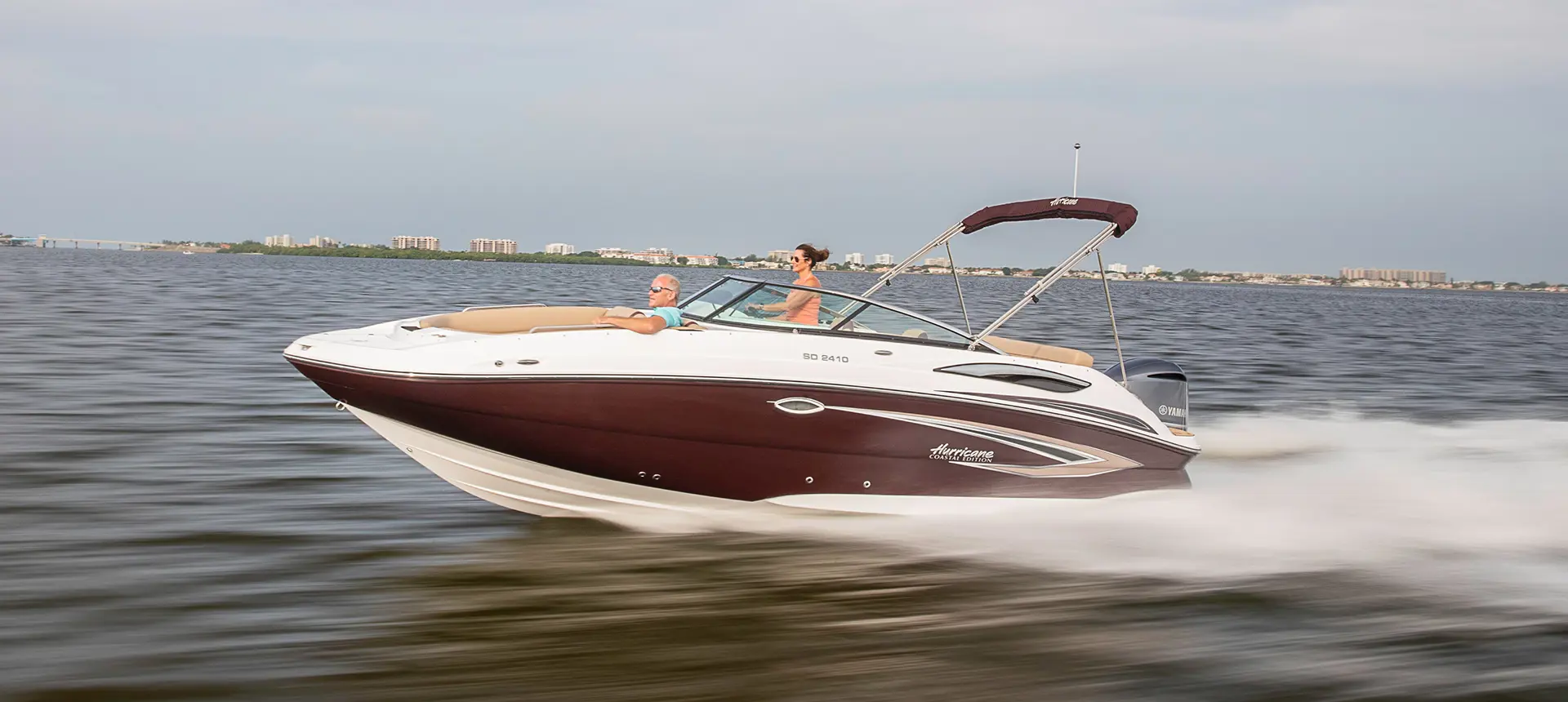 black cherry hurricane sundeck 2410 OB deck boat speeding across a lake