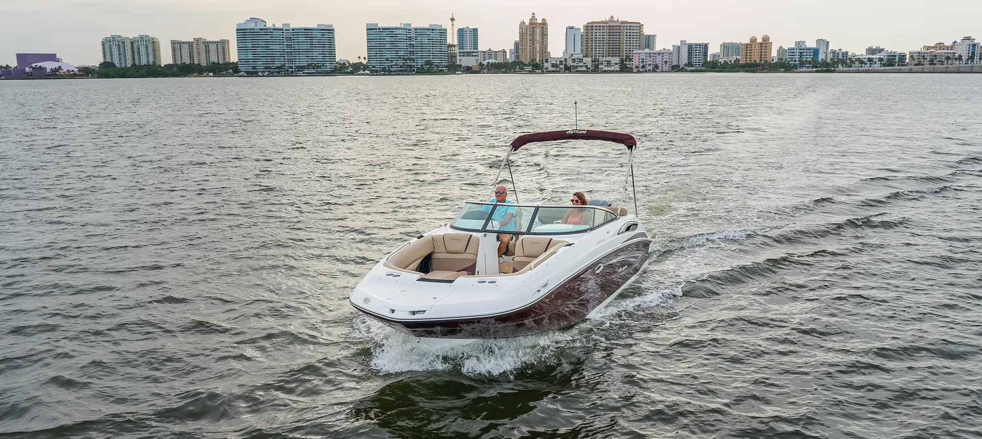 couple cruising across a lake in a black cherry hurricane sundeck 2410 OB deck boat