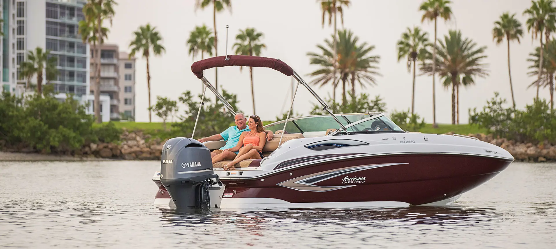 couple relaxing on the stern of their black cherry hurricane sundeck 2410 OB deck boat with hyper platinum graphics