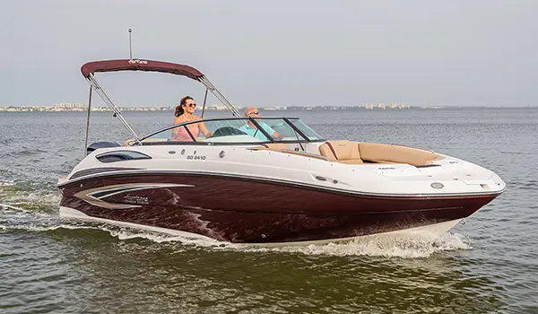 woman driving a black cherry hurricane sundeck 2410 OB deck boat on a lake