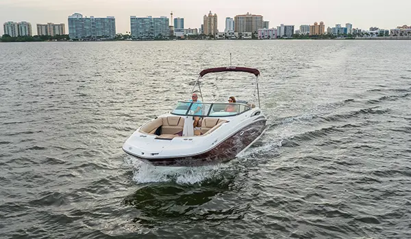 couple cruising across a lake in a black cherry hurricane sundeck 2410 OB deck boat