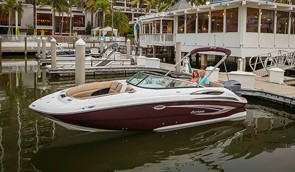 couple sitting on a docked black cherry hurricane sundeck 2410 OB deck boat with hyper platinum graphics