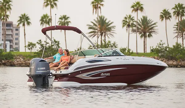 couple relaxing on the stern of their black cherry hurricane sundeck 2410 OB deck boat with hyper platinum graphics