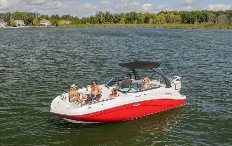 blaze red hurricane sundeck 2486 OB deck boat floating on a lake