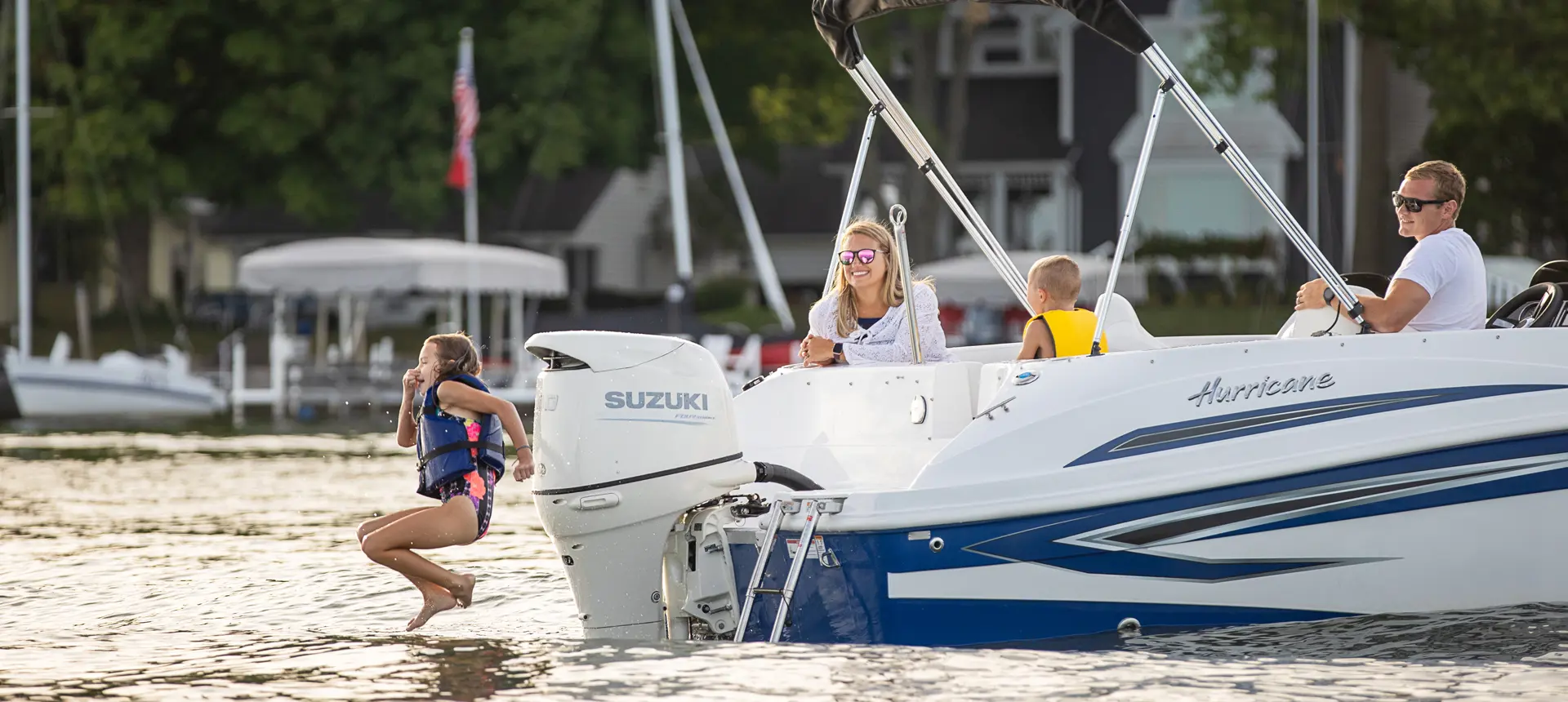 girl jumping into the water off the stern of a hurricane sundeck sport ob deck boat