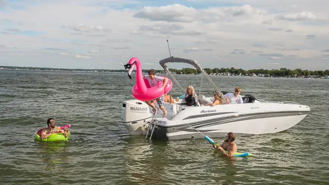 boy jumping into the water off the stern of a hurricane sundeck sport ob deck boat