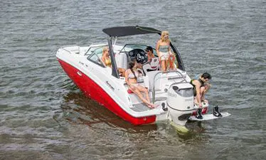 man preparing to wakeboard behind a hurricane sundeck 2496 OB deck boat