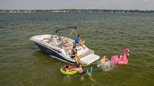 family swimming near their hurricane sundeck sport i/o deck boat
