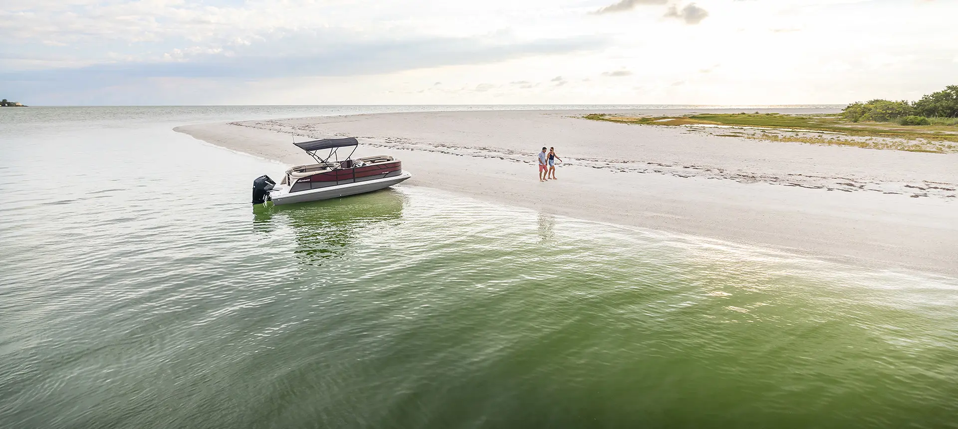 couple walking on the beach near their hurricane fundeck boat