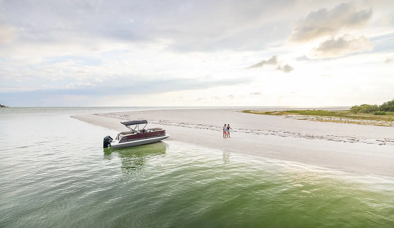 couple walking on the beach near their hurricane fundeck boat