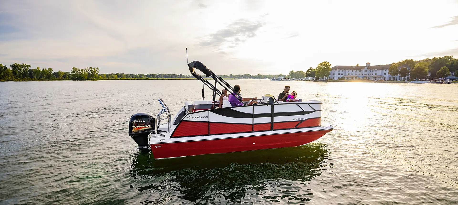 side view of a red hurricane fundeck boat floating on a lake
