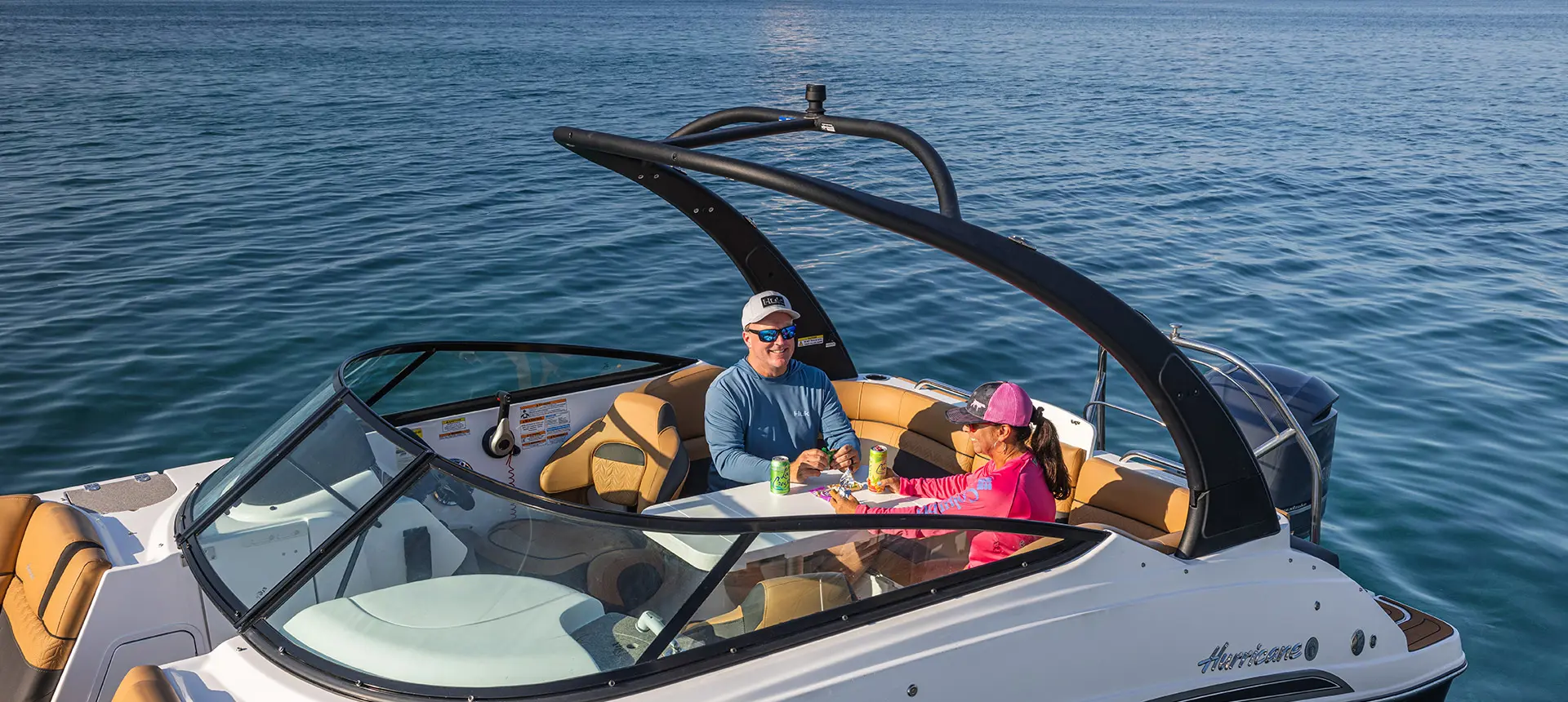 Side view of a couple enjoying drinks and snacks on a Hurricane SunDeck 2486 OB.