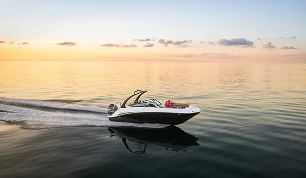 Side view of a Hurricane SunDeck 2486 OB cruising at sunset.