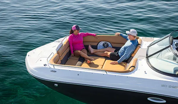 Couple relaxing in front seating of a Hurricane SunDeck 2486 OB.