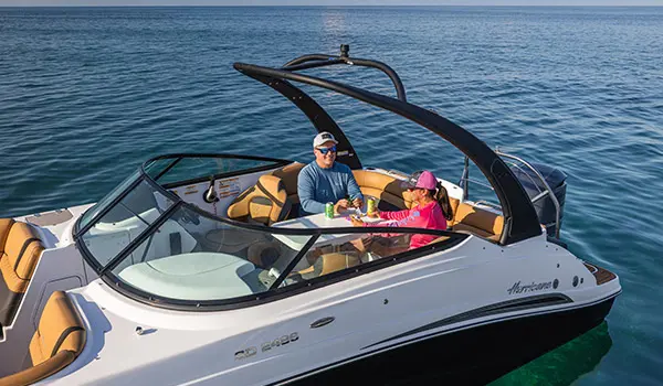 Side view of a couple enjoying drinks and snacks on a Hurricane SunDeck 2486 OB.