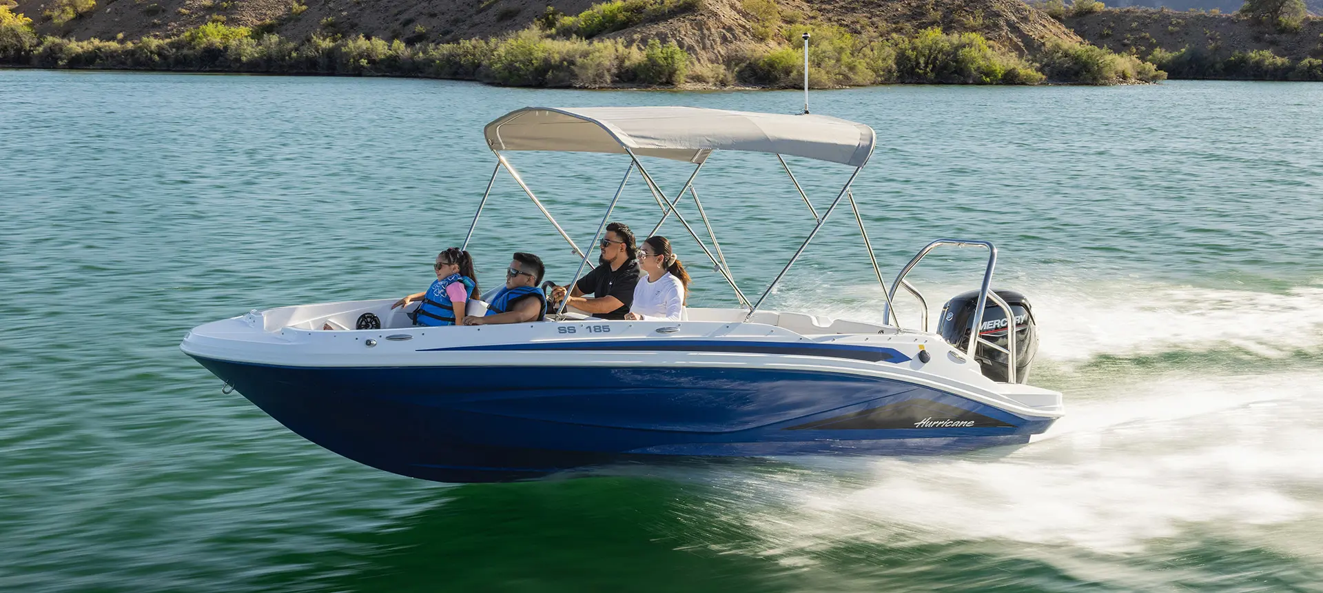 Family on a Hurricane SunDeck Sport 185 OB deck boat cruising on a lake.