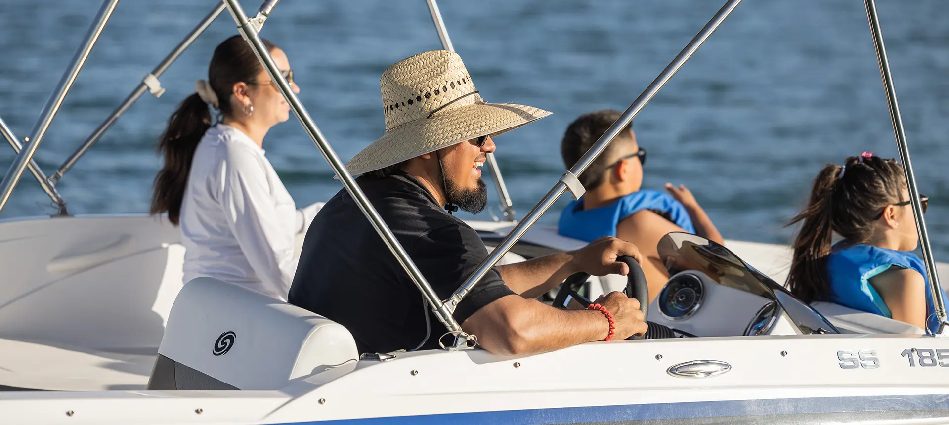 Man smiling at the helm of a Hurricane SunDeck Sport 185 OB deck boat.