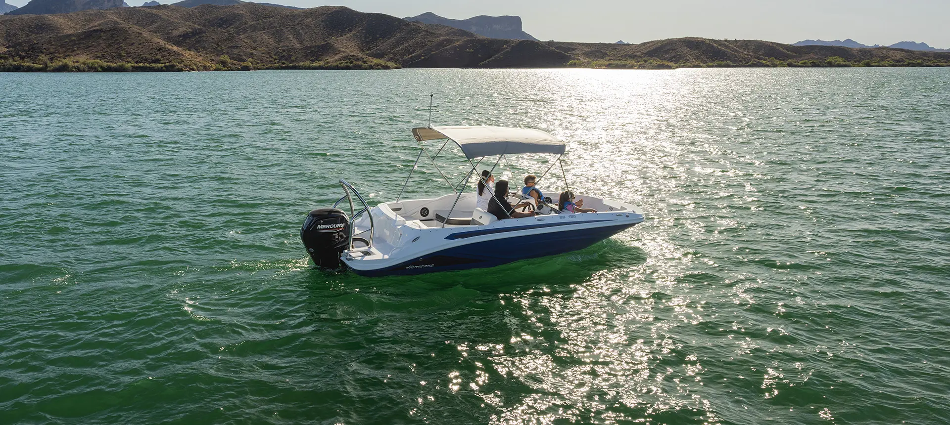 Aerial view of a Hurricane SunDeck Sport 185 OB deck boat floating on a lake.