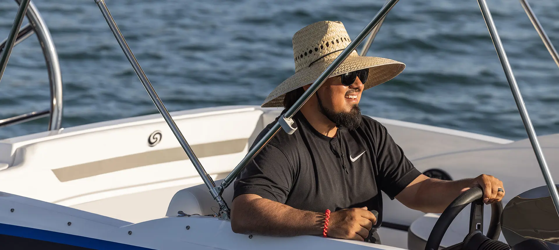 Man smiling at the helm of a Hurricane SunDeck Sport 185 OB deck boat.