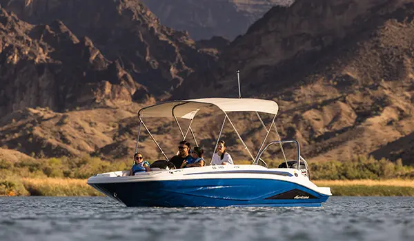 Side profile of a Hurricane SunDeck Sport 185 OB floating on a lake.