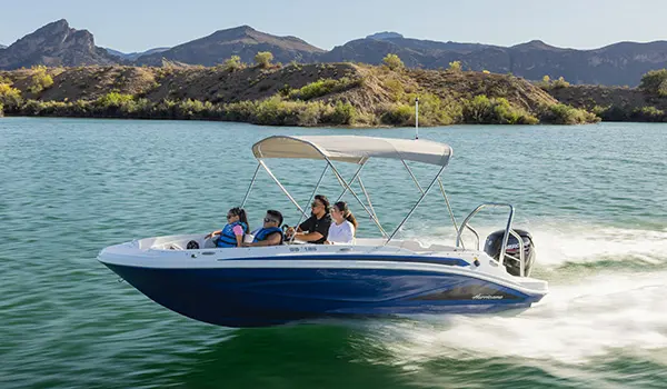 Family on a Hurricane SunDeck Sport 185 OB deck boat cruising on a lake.