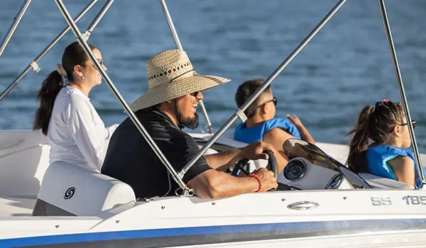Man smiling at the helm of a Hurricane SunDeck Sport 185 OB deck boat.
