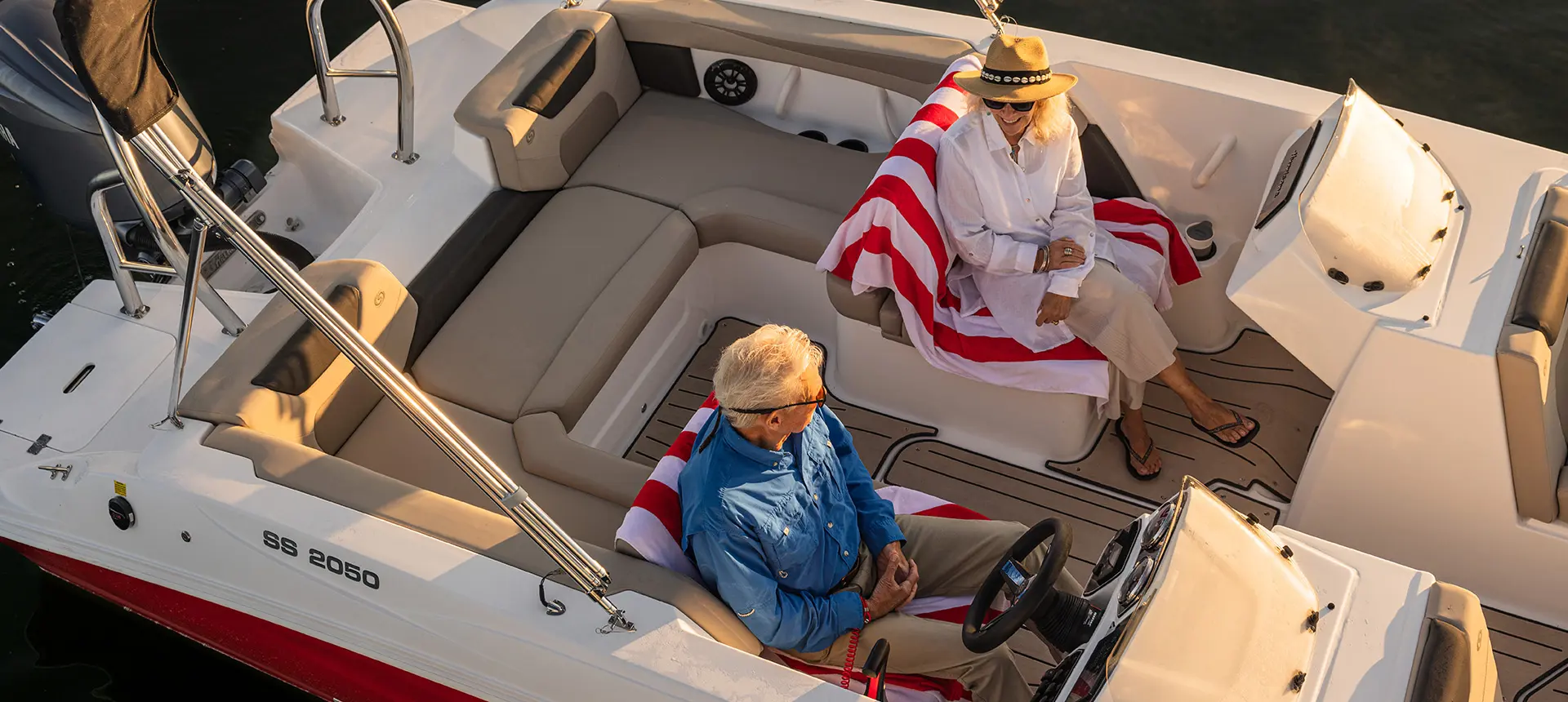 Aerial view of a couple smiling at each other on a Hurricane SunDeck Sport 2050 OB deck boat.