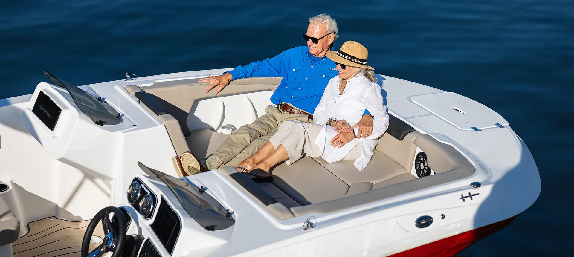 Couple relaxing on the bow of a Hurricane SunDeck Sport 2050 OB deck boat.