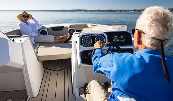 Woman smiling to her husband while he's driving a Hurricane SunDeck Sport 2050 OB deck boat.