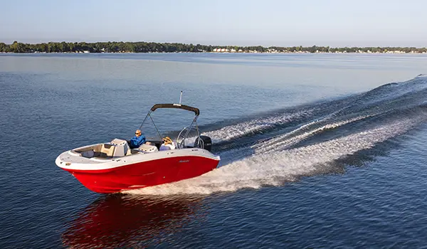 Aerial view of a Hurricane SunDeck Sport 2050 OB deck boat cruising across a lake.