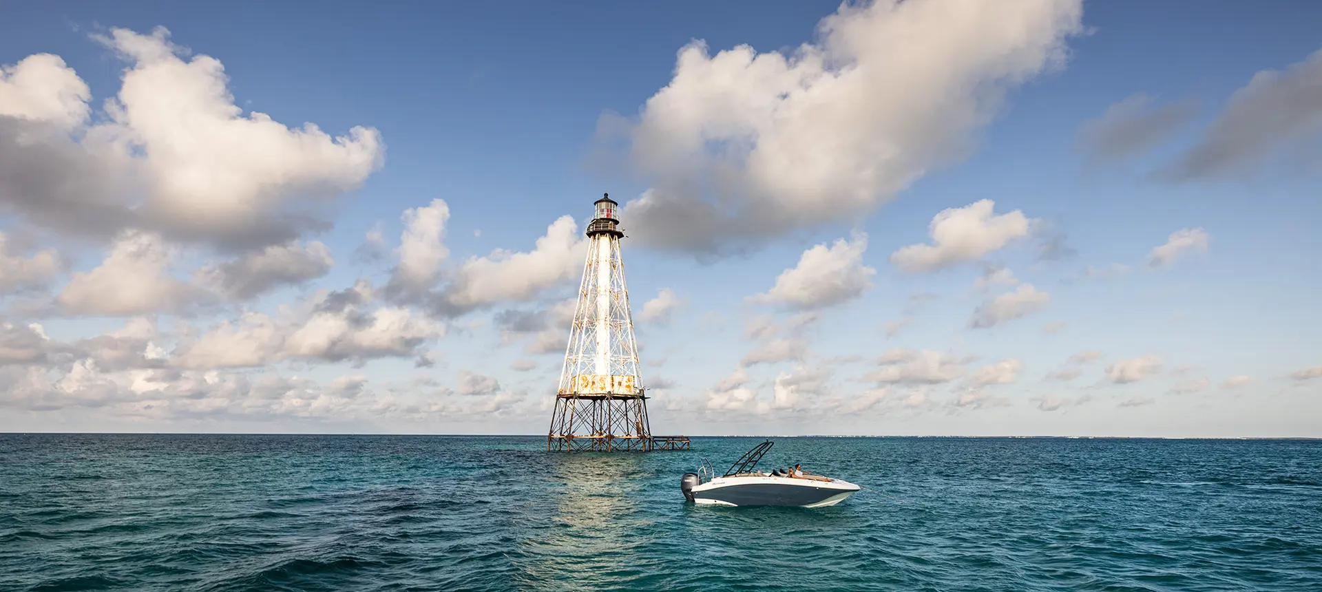 Side view of a Hurricane SunDeck Sport 218 OB deck boat floating on the ocean.