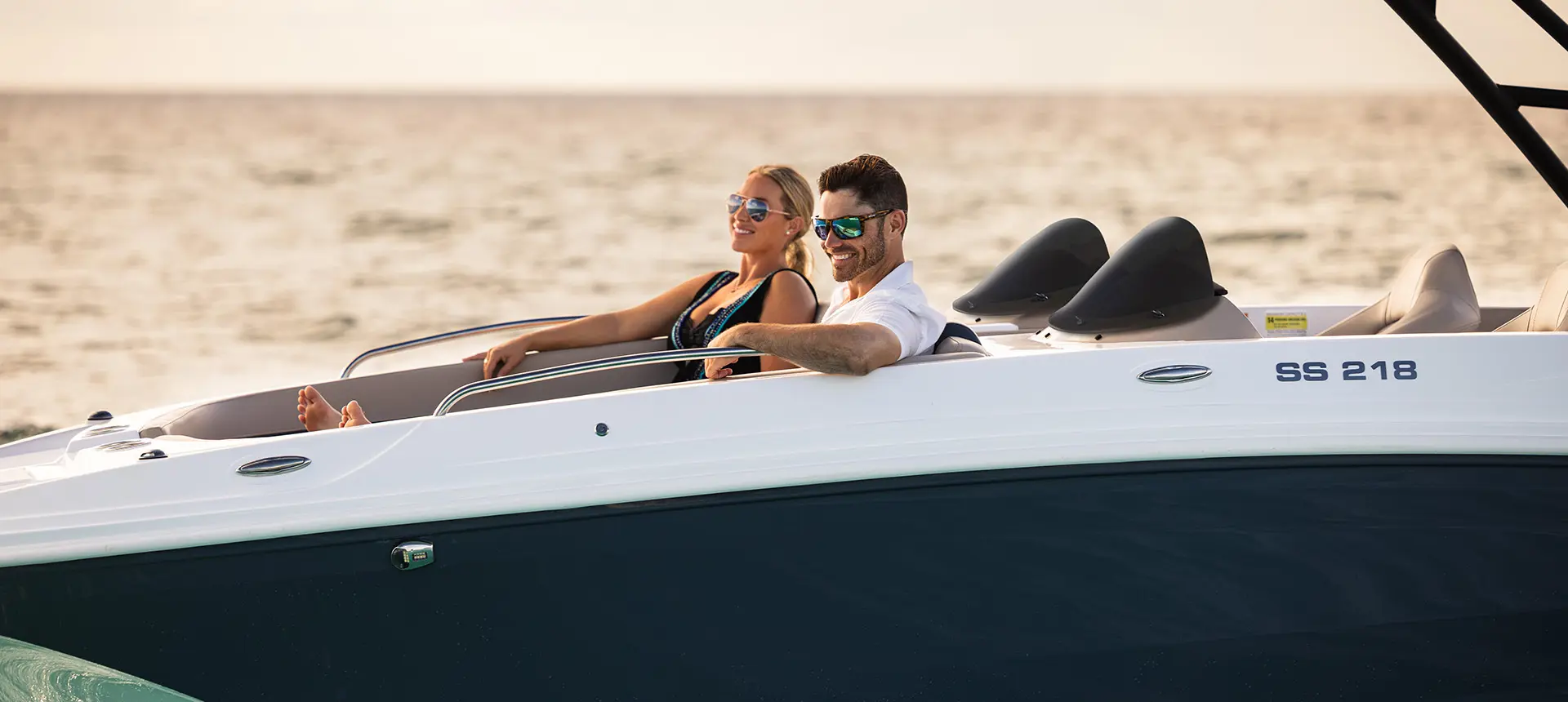 A couple relaxing on the bow seating of a Hurricane SunDeck Sport 218 OB deck boat.