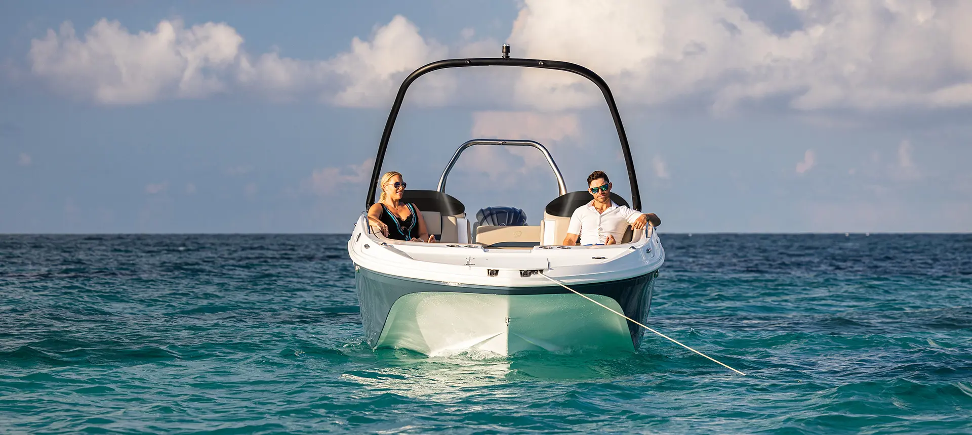 Bow focused view of a couple relaxing on a Hurricane SunDeck Sport 218 OB deck boat.