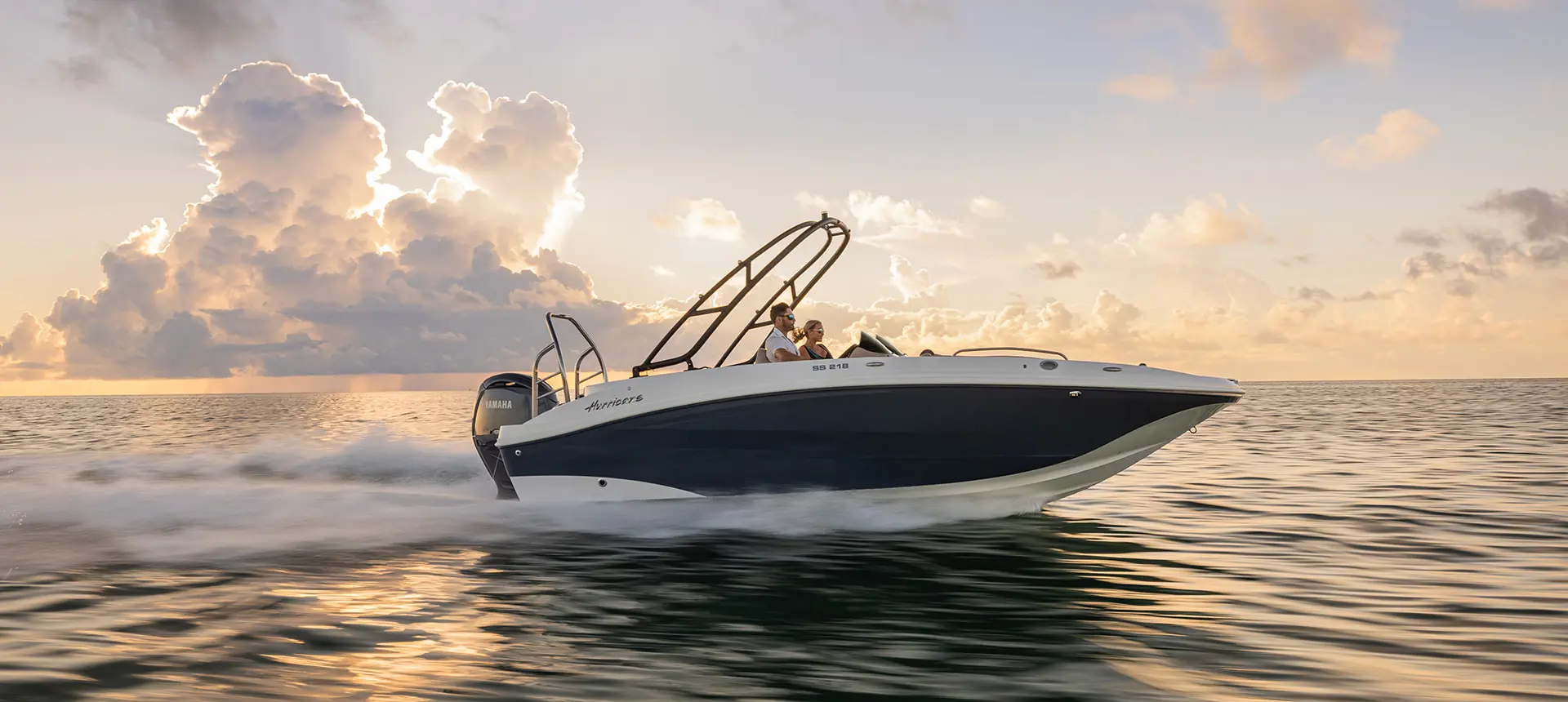 Side view of a Hurricane SunDeck Sport 218 OB deck boat cruising on the ocean.
