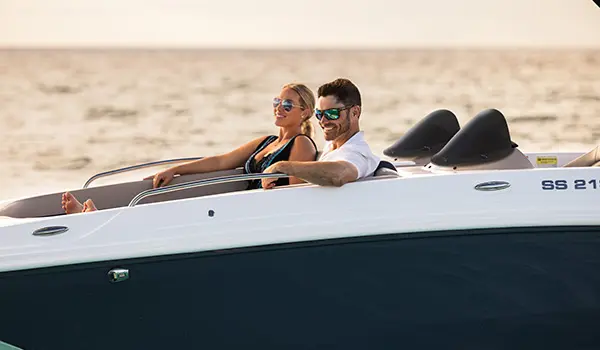 A couple relaxing on the bow seating of a Hurricane SunDeck Sport 218 OB deck boat.