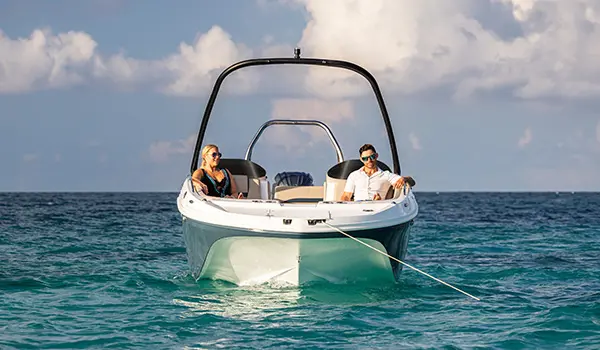 Bow focused view of a couple relaxing on a Hurricane SunDeck Sport 218 OB deck boat.