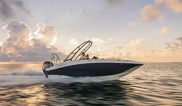 Side view of a Hurricane SunDeck Sport 218 OB deck boat cruising on the ocean.