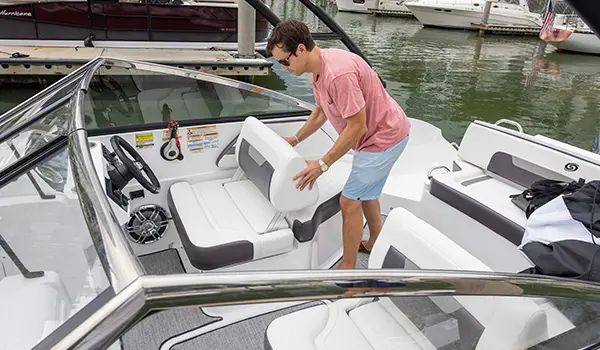 man sets up back rest on captains chair on a hurricane sundeck 235 ob