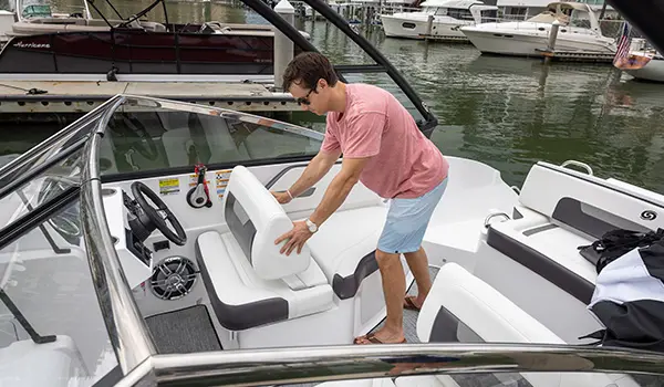 A man pushing the seat back rest backward to create a lounge chair on a Hurricane SunDeck 235 OB deck boat.